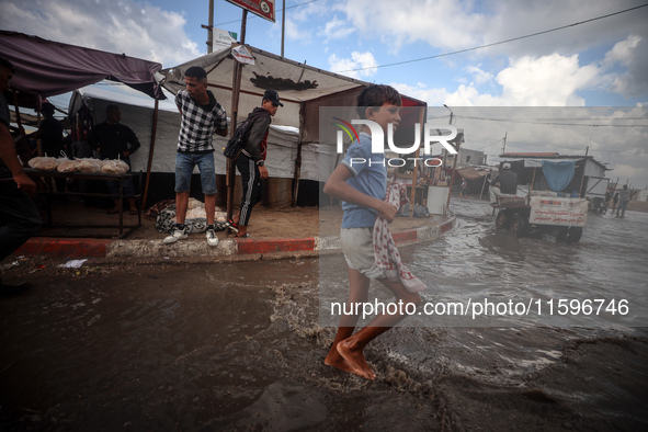 A Palestinian boy walks in a puddle in rainy weather at a camp for displaced people in Khan Yunis, Gaza Strip, on September 22, 2024, amid t...