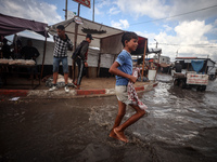 A Palestinian boy walks in a puddle in rainy weather at a camp for displaced people in Khan Yunis, Gaza Strip, on September 22, 2024, amid t...