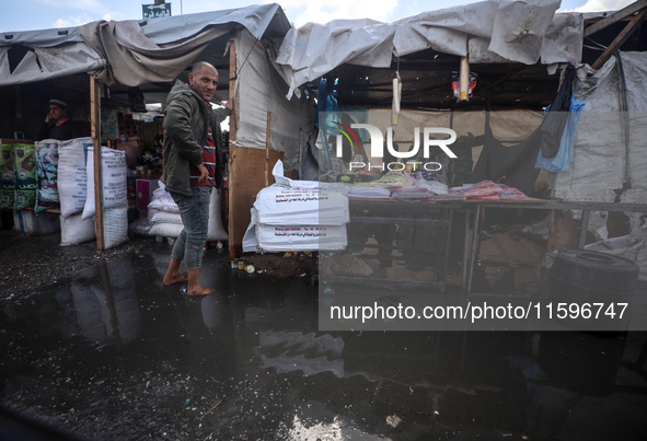 A Palestinian man walks in a puddle in rainy weather at a camp for displaced people in Khan Yunis, Gaza Strip, on September 22, 2024, amid t...