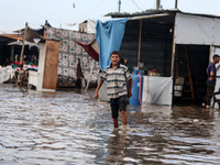 A Palestinian boy walks in a puddle in rainy weather at a camp for displaced people in Khan Yunis, Gaza Strip, on September 22, 2024, amid t...