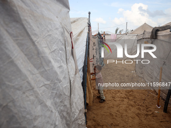 A Palestinian boy looks out from his tent in the Al-Mawasi area in Khan Yunis in the southern Gaza Strip on September 22, 2024, amid the ong...