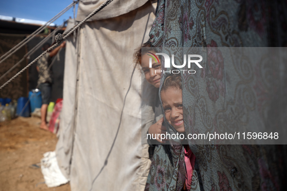 Displaced Palestinian children look out from their tent in the Mawasi area in Khan Younis, southern Gaza Strip, on September 22, 2024, amid...