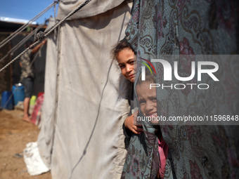 Displaced Palestinian children look out from their tent in the Mawasi area in Khan Younis, southern Gaza Strip, on September 22, 2024, amid...