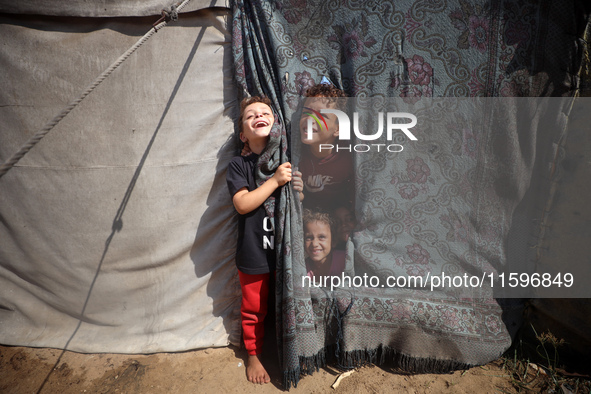 Displaced Palestinian children look out from their tent in the Mawasi area in Khan Younis, southern Gaza Strip, on September 22, 2024, amid...