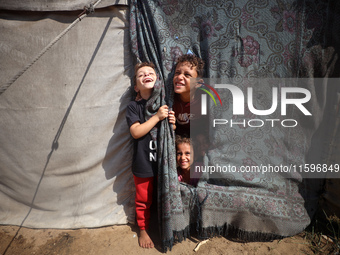 Displaced Palestinian children look out from their tent in the Mawasi area in Khan Younis, southern Gaza Strip, on September 22, 2024, amid...