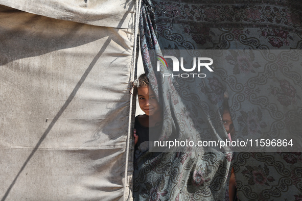 Displaced Palestinian children look out from their tent in the Mawasi area in Khan Younis, southern Gaza Strip, on September 22, 2024, amid...