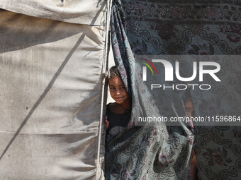 Displaced Palestinian children look out from their tent in the Mawasi area in Khan Younis, southern Gaza Strip, on September 22, 2024, amid...