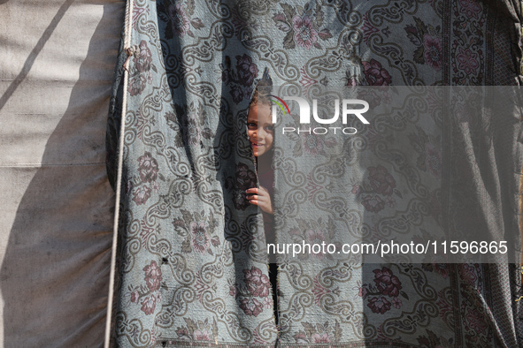 A Palestinian boy looks out from his tent in the Al-Mawasi area in Khan Yunis in the southern Gaza Strip on September 22, 2024, amid the ong...