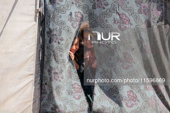 Displaced Palestinian children look out from their tent in the Mawasi area in Khan Younis, southern Gaza Strip, on September 22, 2024, amid...