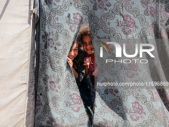 Displaced Palestinian children look out from their tent in the Mawasi area in Khan Younis, southern Gaza Strip, on September 22, 2024, amid...