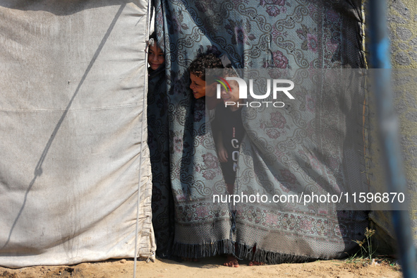 Displaced Palestinian children look out from their tent in the Mawasi area in Khan Younis, southern Gaza Strip, on September 22, 2024, amid...