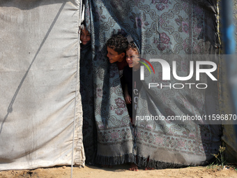 Displaced Palestinian children look out from their tent in the Mawasi area in Khan Younis, southern Gaza Strip, on September 22, 2024, amid...