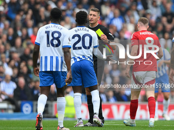 Referee Robert Jones shows a yellow card to Carlos Baleba of Brighton during the Premier League match between Brighton and Hove Albion and N...