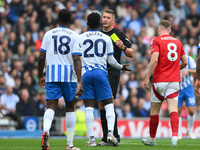 Referee Robert Jones shows a yellow card to Carlos Baleba of Brighton during the Premier League match between Brighton and Hove Albion and N...