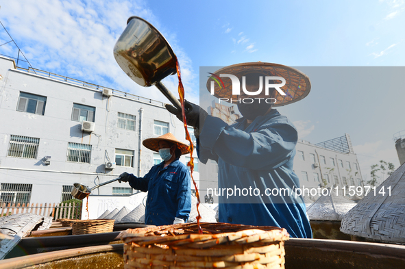 Workers stir soy sauce in Tengzhou, China, on September 21, 2024. 