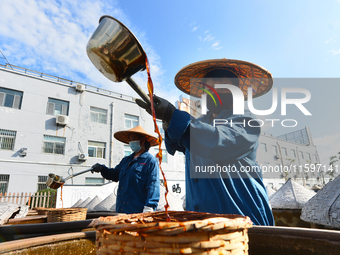 Workers stir soy sauce in Tengzhou, China, on September 21, 2024. (