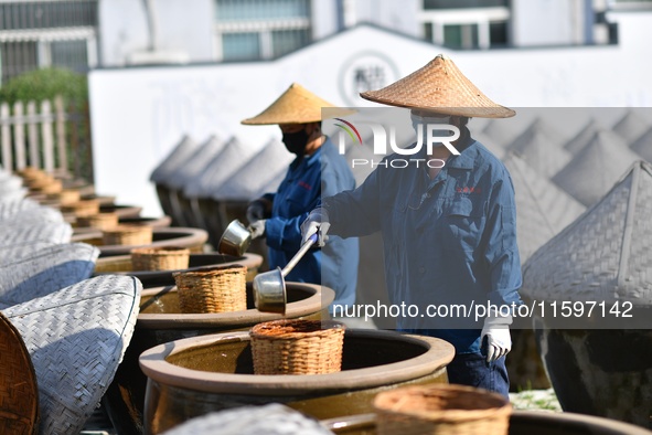 Workers stir soy sauce in Tengzhou, China, on September 21, 2024. 