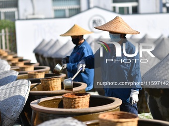 Workers stir soy sauce in Tengzhou, China, on September 21, 2024. (