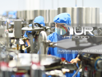 Workers operate in front of vacuum sealing machines in Tengzhou, China, on September 21, 2024. (