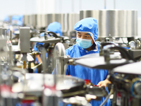 Workers operate in front of vacuum sealing machines in Tengzhou, China, on September 21, 2024. (