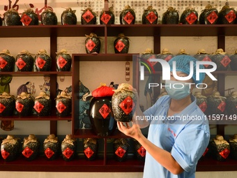 A worker shows a soy sauce packaging style in Tengzhou, China, on September 21, 2024. (