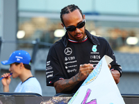 Lewis Hamilton of the United Kingdom and Mercedes-AMG Petronas F1 Team signs a poster during the drivers' parade ahead of the F1 Grand Prix...