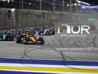 Lando Norris of the United Kingdom and McLaren Formula 1 Team drives on the opening lap during the F1 Grand Prix of Singapore at Marina Bay...