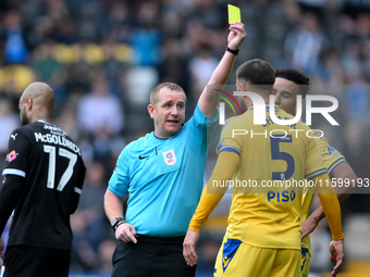 Referee Lee Swabey shows a yellow card to Max Ehmer of Gillingham during the Sky Bet League 2 match between Notts County and Gillingham at M...