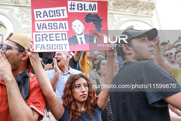 A female demonstrator raises a placard with a caricature of the Tunisian president Kais Saied that reads, ''racist, vassal, greed, fascist,'...