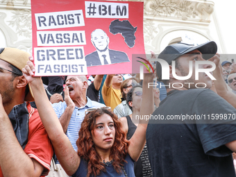 A female demonstrator raises a placard with a caricature of the Tunisian president Kais Saied that reads, ''racist, vassal, greed, fascist,'...