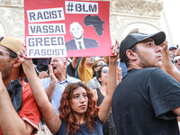 A female demonstrator raises a placard with a caricature of the Tunisian president Kais Saied that reads, ''racist, vassal, greed, fascist,'...