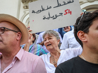 An elderly female demonstrator shouts slogans as she raises a placard that reads, ''Down with the regime of July 54,'' during a demonstratio...