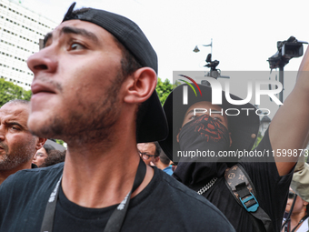 A young demonstrator with his face covered by a bandanna waves his arm during a demonstration organized by the Tunisian Network for Rights a...