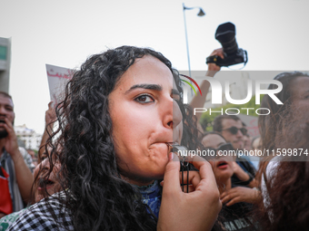 A young female demonstrator blows a whistle during a demonstration organized by the Tunisian Network for Rights and Freedoms in Tunis, Tunis...