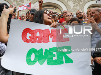 A female demonstrator shouts slogans as she holds a placard that reads ''Game Over'' during a demonstration organized by the Tunisian Networ...