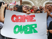 A female demonstrator shouts slogans as she holds a placard that reads ''Game Over'' during a demonstration organized by the Tunisian Networ...