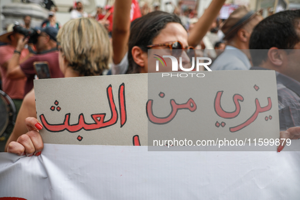 A female demonstrator holds a placard that reads in Arabic, ''Enough with absurdity,'' during a demonstration organized by the Tunisian Netw...