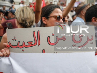 A female demonstrator holds a placard that reads in Arabic, ''Enough with absurdity,'' during a demonstration organized by the Tunisian Netw...