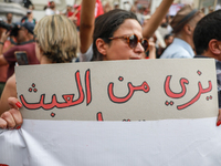 A female demonstrator holds a placard that reads in Arabic, ''Enough with absurdity,'' during a demonstration organized by the Tunisian Netw...