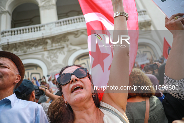 A female demonstrator shouts slogans as she waves the national flag of Tunisia during a demonstration organized by the Tunisian Network for...