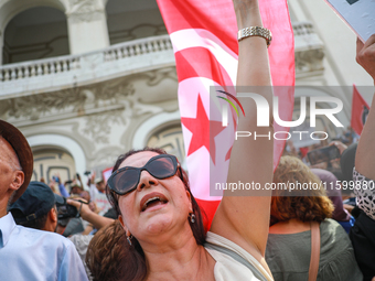 A female demonstrator shouts slogans as she waves the national flag of Tunisia during a demonstration organized by the Tunisian Network for...