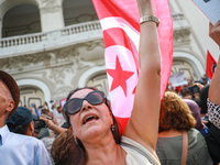 A female demonstrator shouts slogans as she waves the national flag of Tunisia during a demonstration organized by the Tunisian Network for...