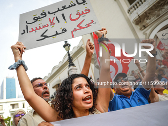 A female demonstrator shouts slogans as she raises a placard that reads in Arabic, ''Tunisian people wake up, the tyranny rules over you,''...