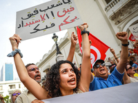 A female demonstrator shouts slogans as she raises a placard that reads in Arabic, ''Tunisian people wake up, the tyranny rules over you,''...