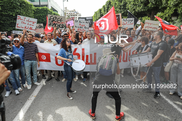 Demonstrators wave national Tunisian flags and raise placards during a demonstration organized by the Tunisian Network for Rights and Freedo...