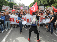 Demonstrators wave national Tunisian flags and raise placards during a demonstration organized by the Tunisian Network for Rights and Freedo...