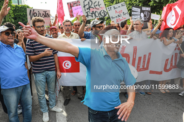 A demonstrator shouts slogans as others raise placards and wave the national flag of Tunisia during a demonstration organized by the Tunisia...