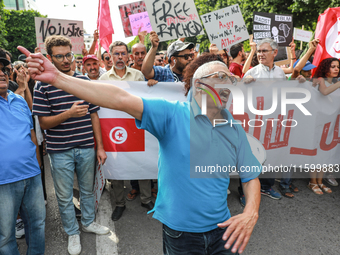 A demonstrator shouts slogans as others raise placards and wave the national flag of Tunisia during a demonstration organized by the Tunisia...