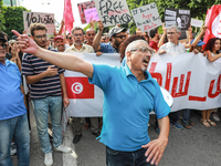 A demonstrator shouts slogans as others raise placards and wave the national flag of Tunisia during a demonstration organized by the Tunisia...