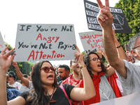 A young female demonstrator shouts slogans as she raises a placard that reads, ''If you are not angry, you are not paying attention,'' durin...